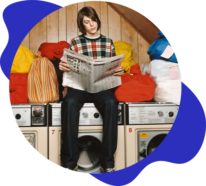 A person sitting on top of a washing machine reading.